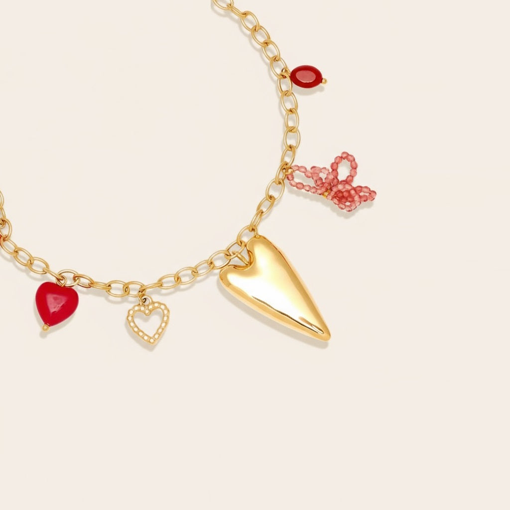 A gold-colored necklace with various charms, including a heart-shaped charm, a butterfly charm, and a red heart-shaped charm.