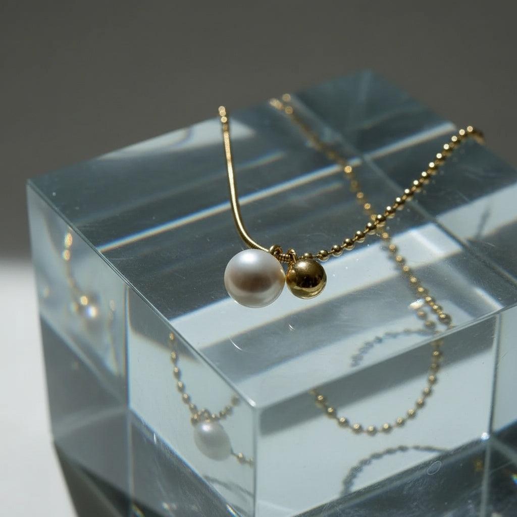 "Rana" – Goldfarbene Halskette mit Süßwasserperle & Kugelanhänger (42+5 cm)